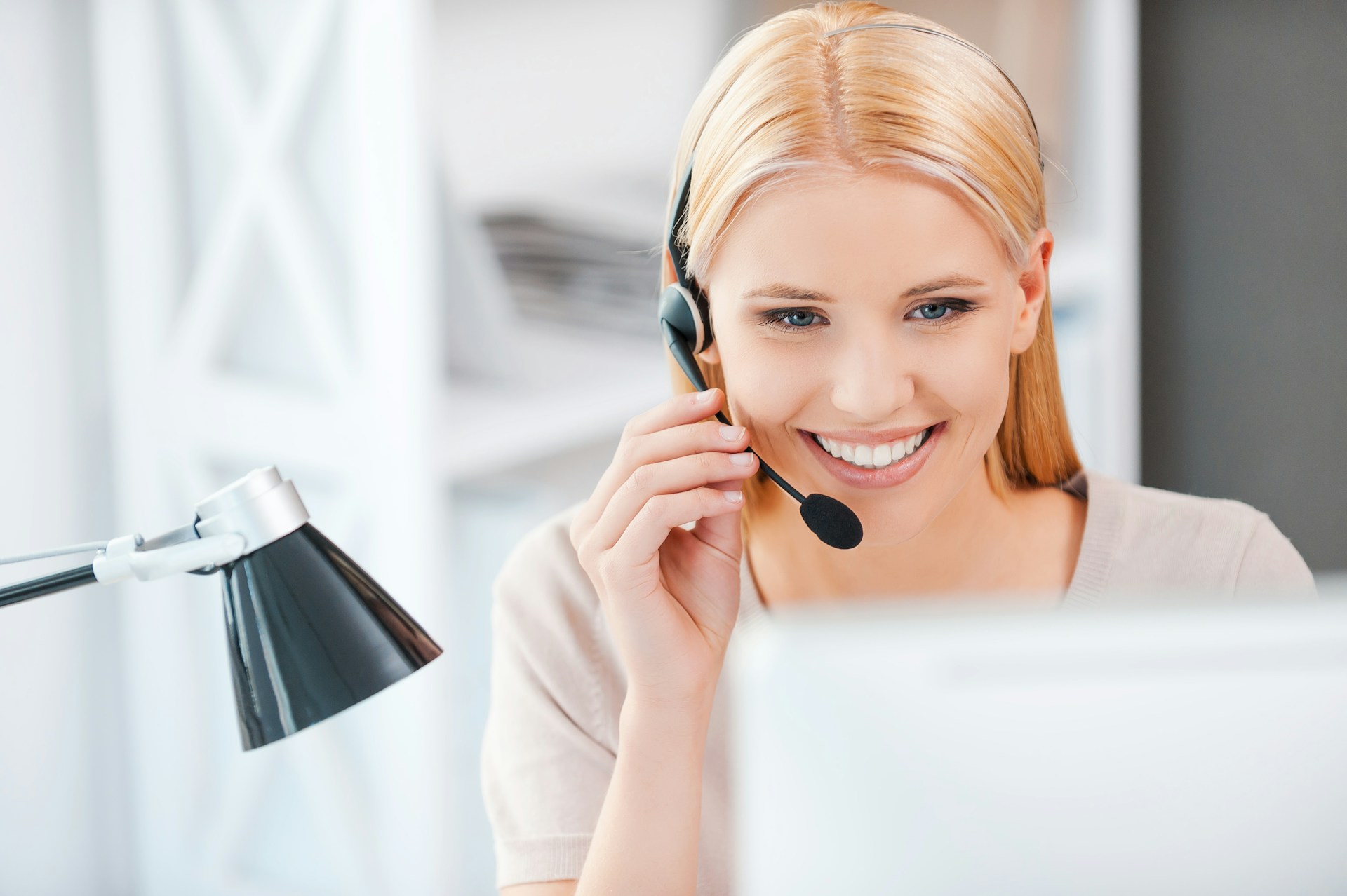 A smiling woman wearing a headset to talk to customers