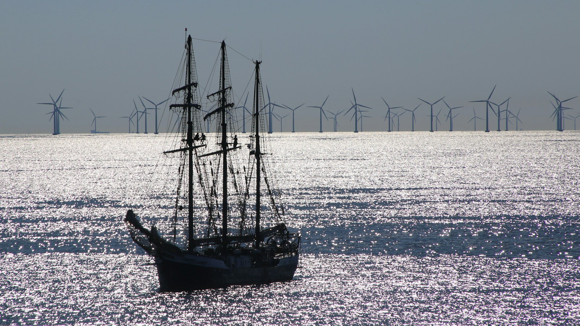 A sailing ship passing an offshore wind farm