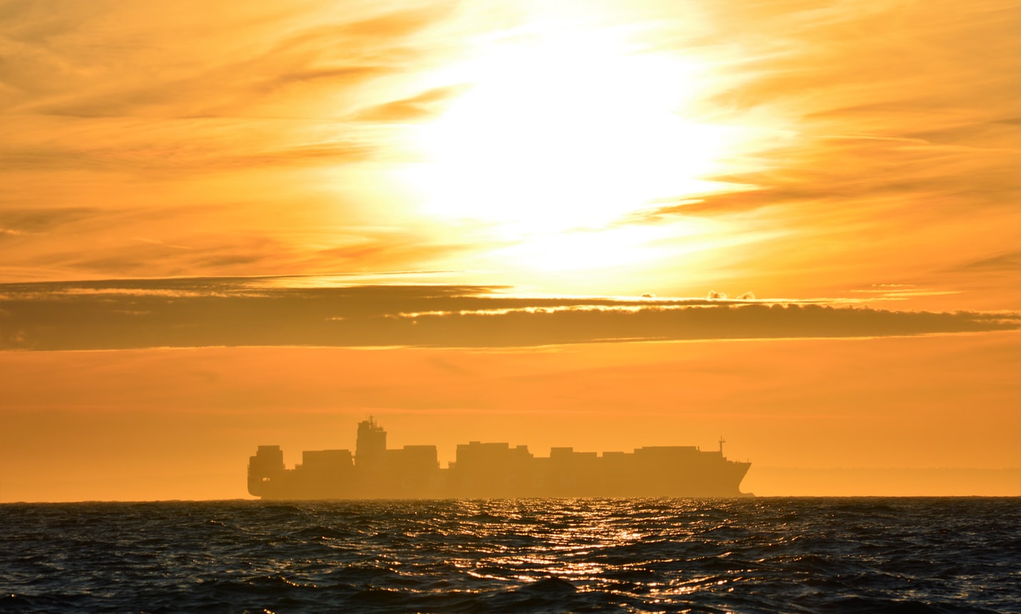 silhouette of a container ship on the horizon at sunset