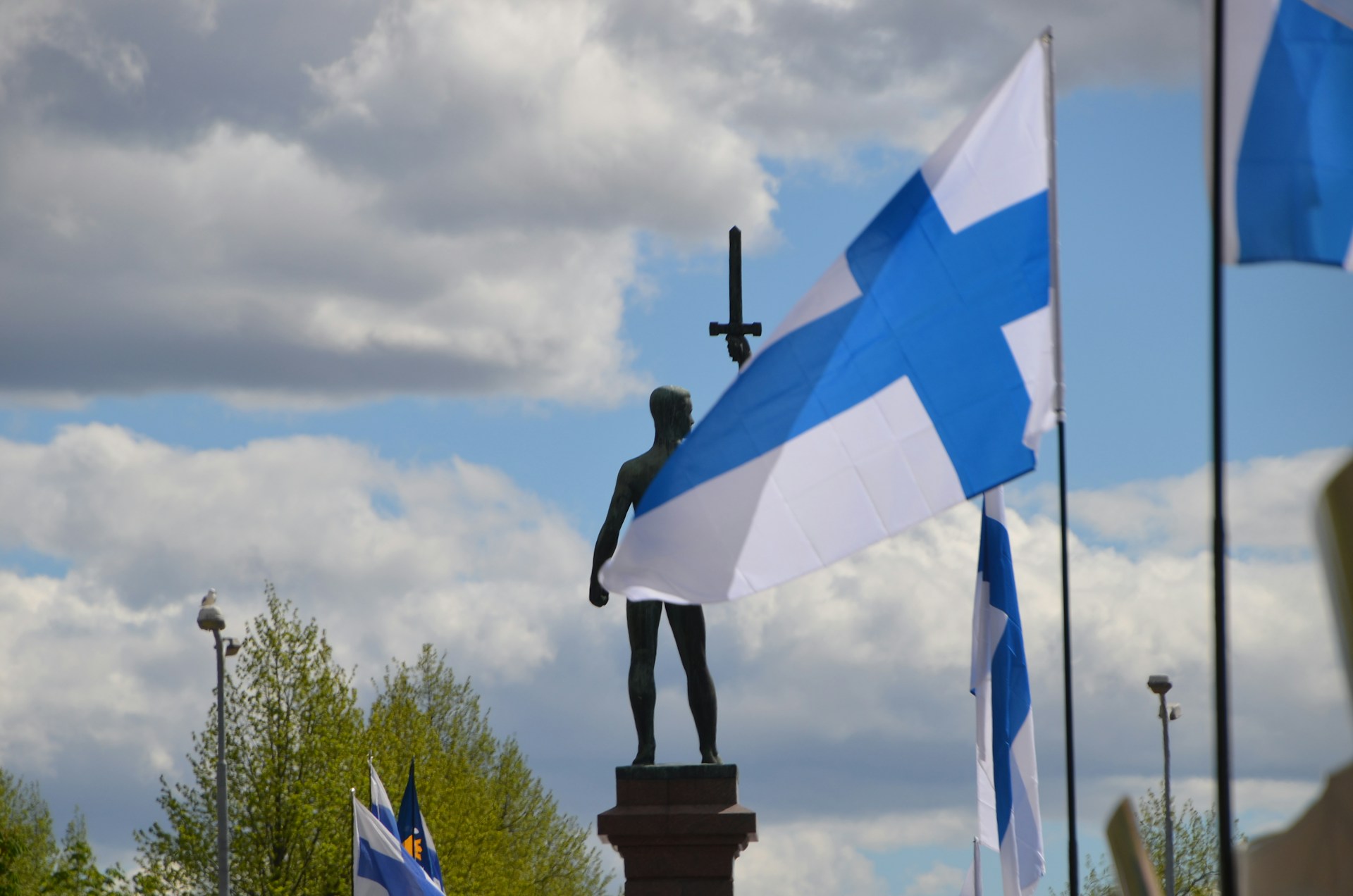 The Finnish flag flying in front of a warrior statue