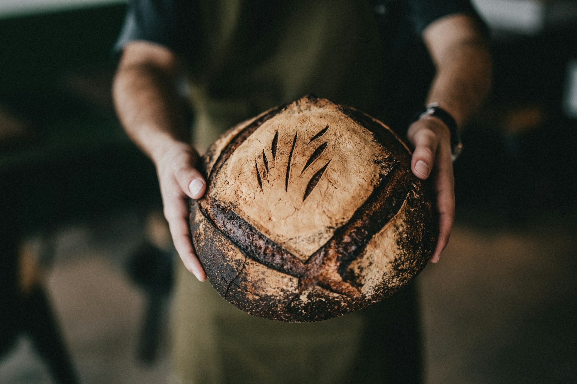 A baker holding out a loaf of bread