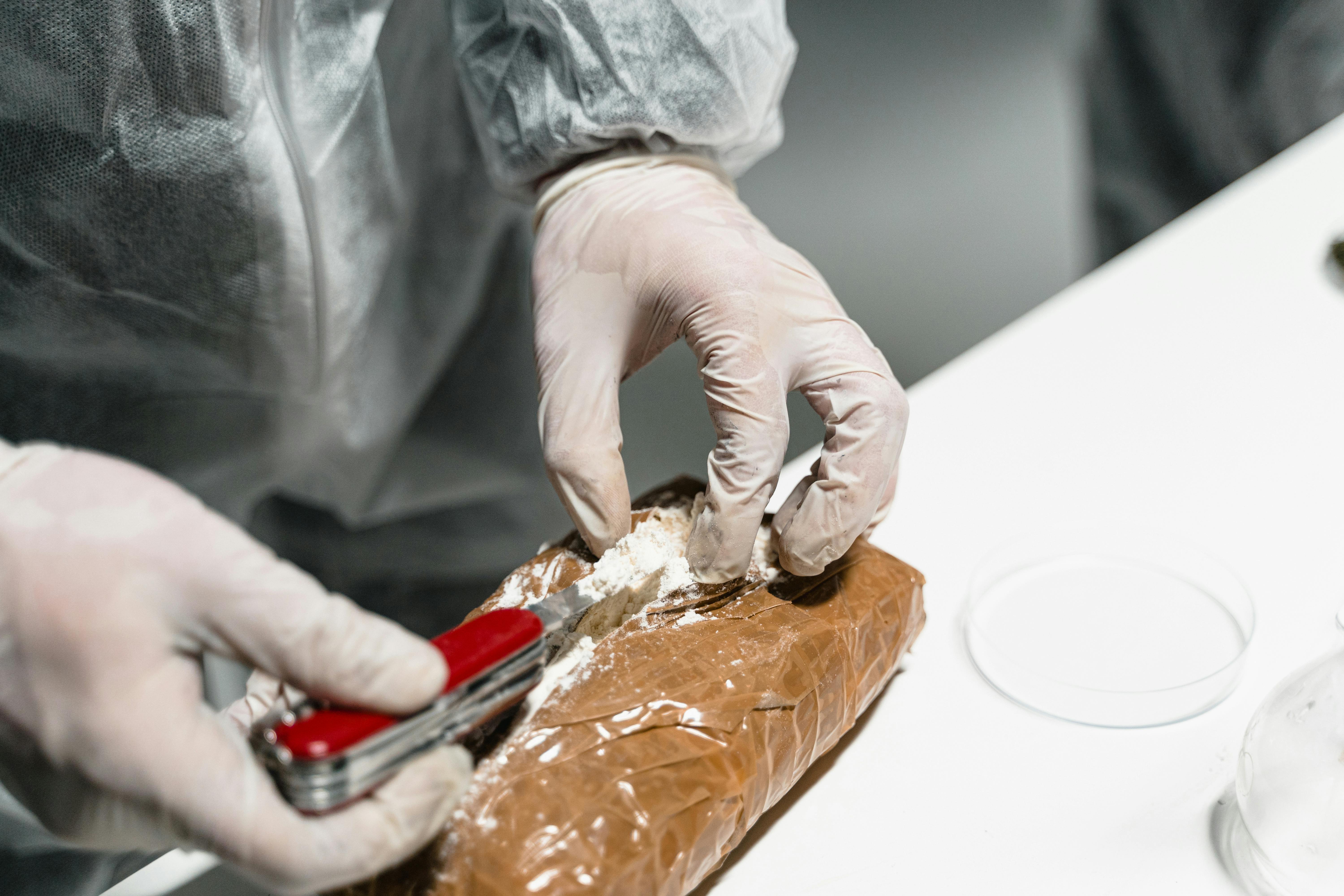 Person in lab opening a packet of cocaine for testing