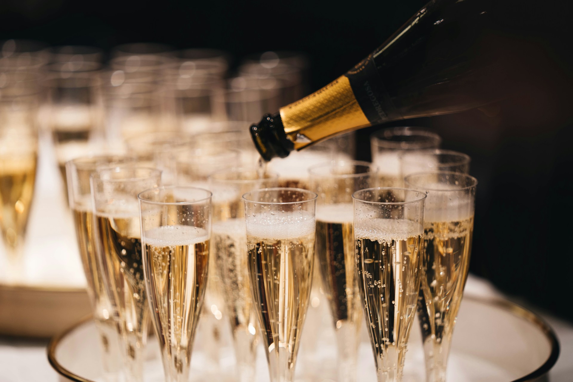 Champagne being poured into a tray of flutes