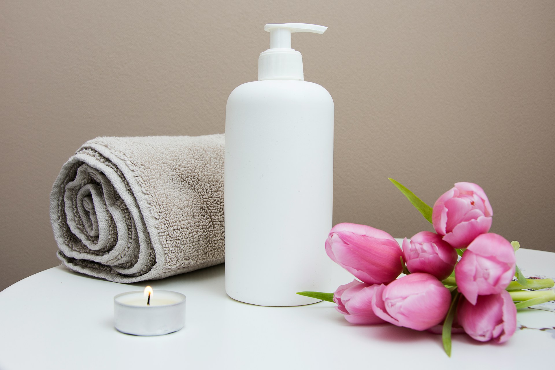 A towel, lotion, candle and flowers in a spa setting