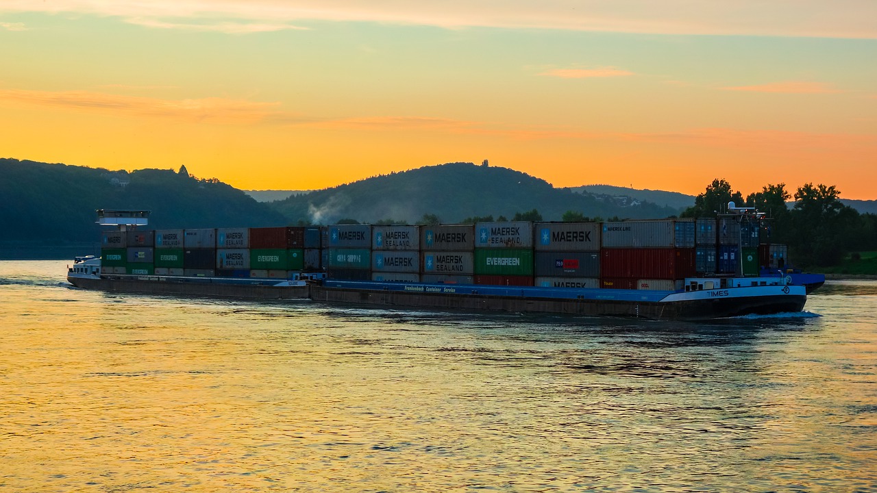 A cargo ship sailing near the coastline at dusk