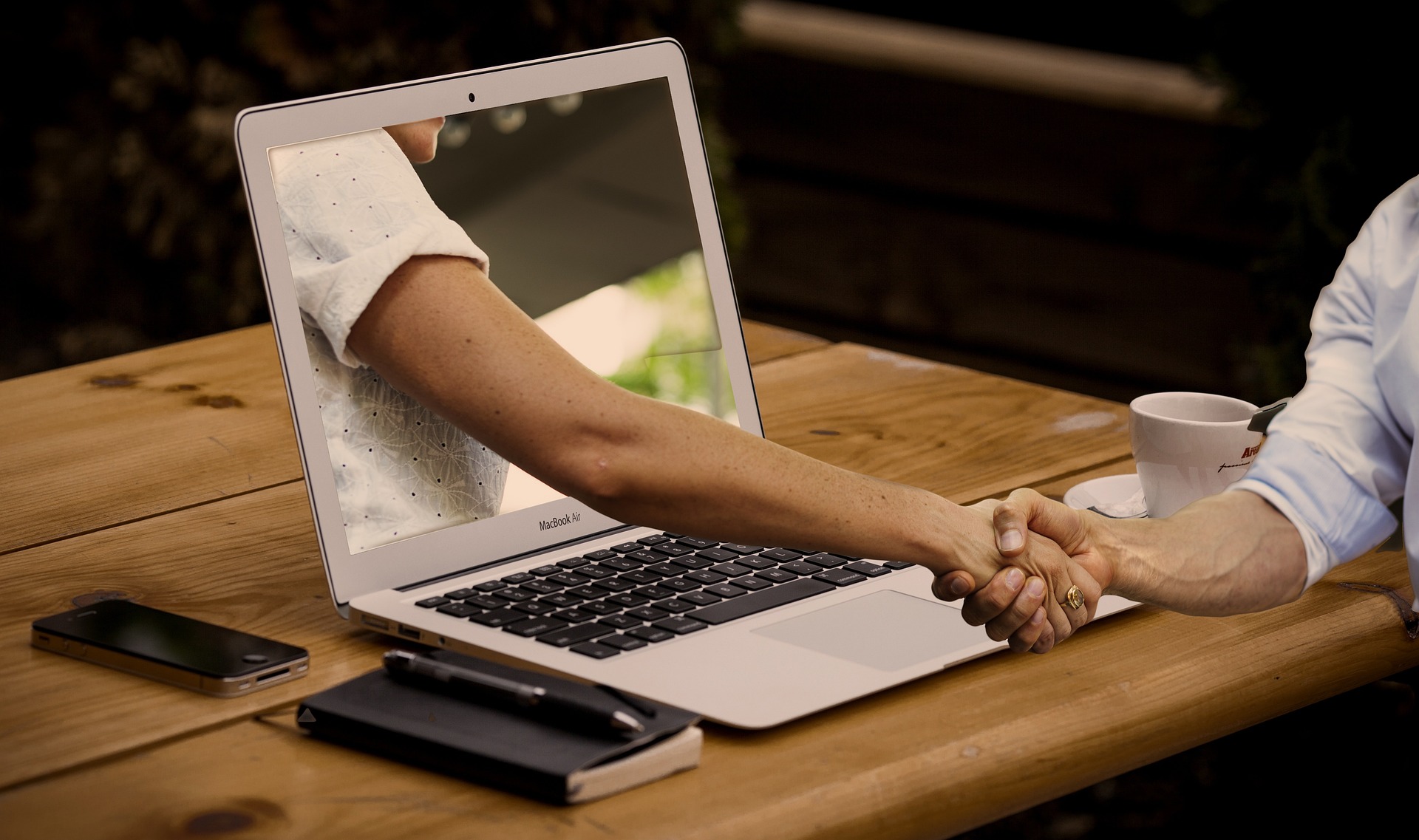 People shaking hands through laptop screen