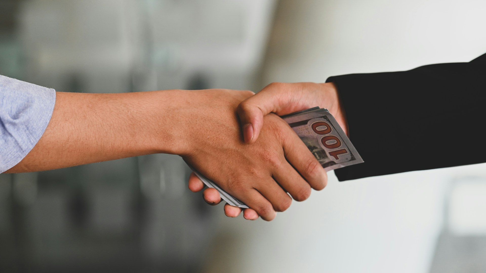 Men shaking hands while palming money between them