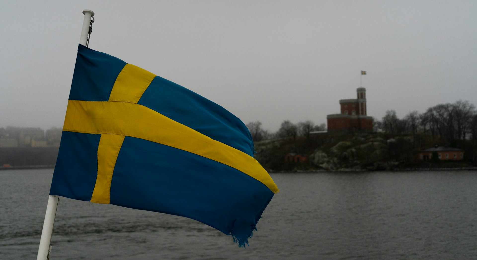 The Swedish flag flying in front of water